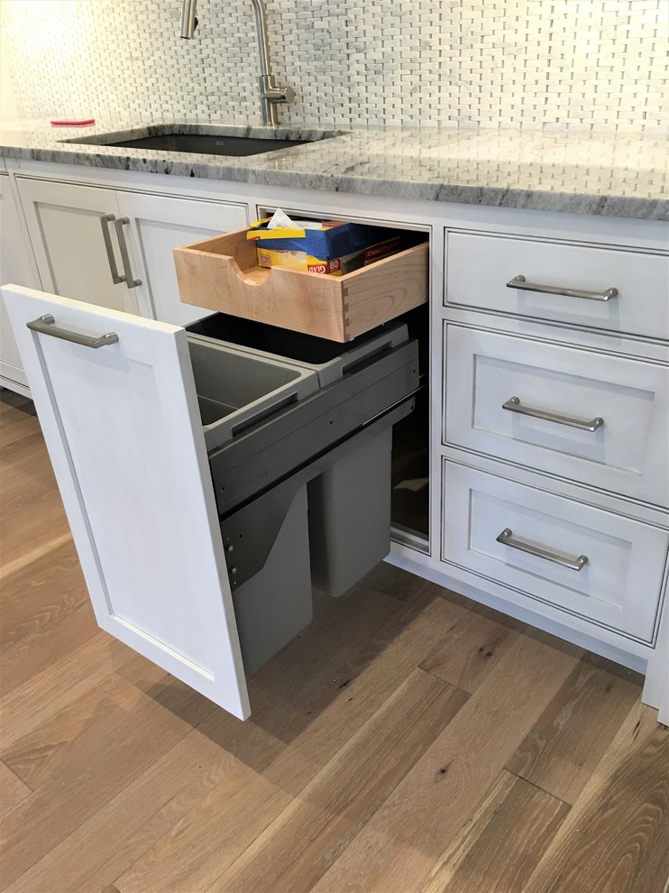 Eat-in kitchen - large transitional l-shaped medium tone wood floor and brown floor eat-in kitchen idea with an undermount sink, flat-panel cabinets, gray cabinets, marble countertops, gray backsplash, marble backsplash, paneled appliances and an island