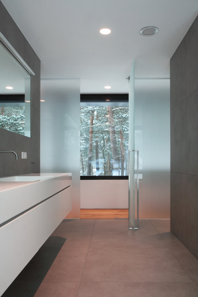 Inspiration for an expansive master bathroom in Hanover with flat-panel cabinets, white cabinets, a freestanding tub, a curbless shower, a one-piece toilet, white tile, stone slab, grey walls, limestone floors, a vessel sink, tile benchtops, grey floor and a sliding shower screen.