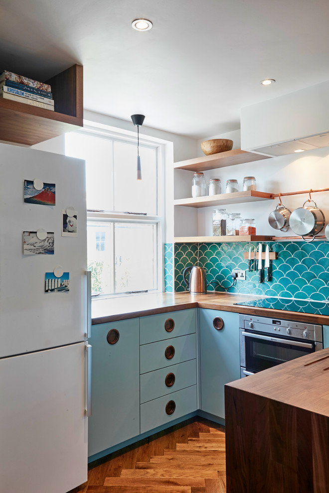 Design ideas for a small midcentury u-shaped separate kitchen in London with a farmhouse sink, flat-panel cabinets, blue cabinets, wood benchtops, green splashback, ceramic splashback, medium hardwood floors, no island and brown floor.