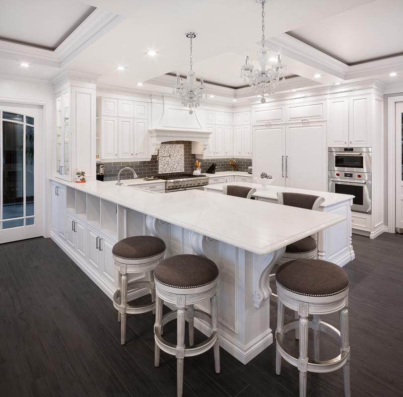 Design ideas for a large transitional eat-in kitchen in New York with a drop-in sink, raised-panel cabinets, white cabinets, quartzite benchtops, metallic splashback, subway tile splashback, panelled appliances, dark hardwood floors, multiple islands, brown floor and white benchtop.