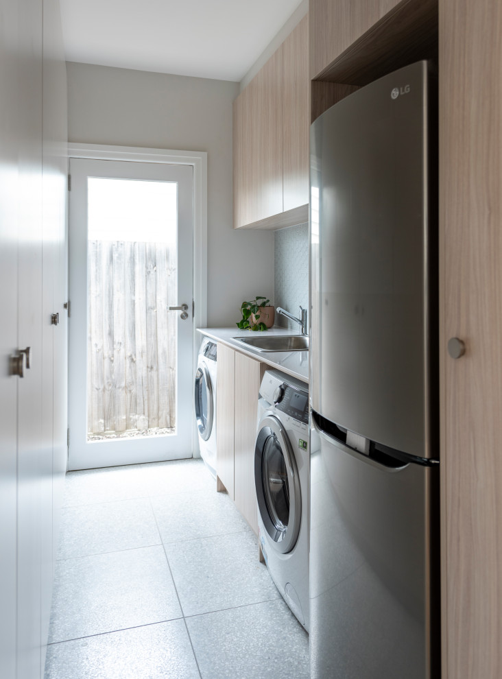 Inspiration for a large contemporary single-wall dedicated laundry room in Melbourne with flat-panel cabinets, light wood cabinets, quartz benchtops, green splashback, mosaic tile splashback, white walls, a side-by-side washer and dryer and white benchtop.