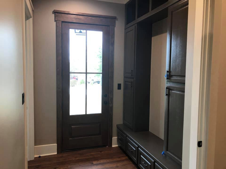 Mid-sized mountain style medium tone wood floor and brown floor mudroom photo with brown walls and a glass front door