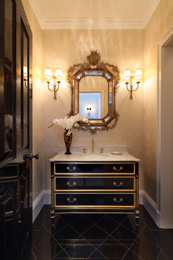 Photo of a large traditional powder room in Los Angeles with furniture-like cabinets, black cabinets, beige walls, porcelain floors, an undermount sink and limestone benchtops.