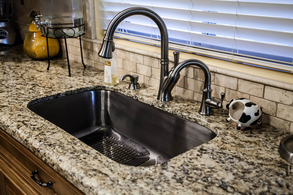 Inspiration for a mid-sized transitional l-shaped travertine floor eat-in kitchen remodel in Phoenix with an undermount sink, raised-panel cabinets, medium tone wood cabinets, granite countertops, beige backsplash, stone tile backsplash, stainless steel appliances and an island