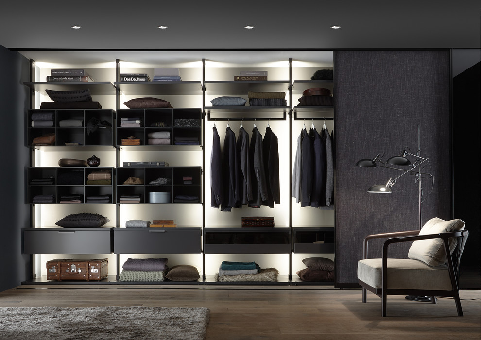 Photo of a mid-sized contemporary men's dressing room in Stuttgart with open cabinets, medium hardwood floors and brown floor.