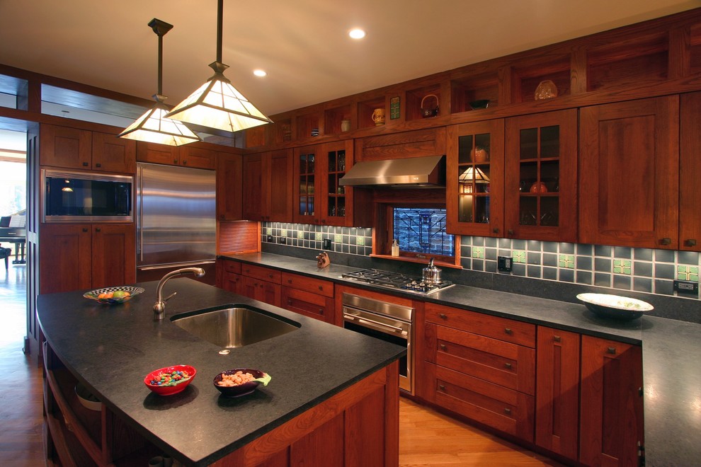 This is an example of a large arts and crafts u-shaped kitchen in Chicago with shaker cabinets, stainless steel appliances, an undermount sink, dark wood cabinets, green splashback, with island and medium hardwood floors.