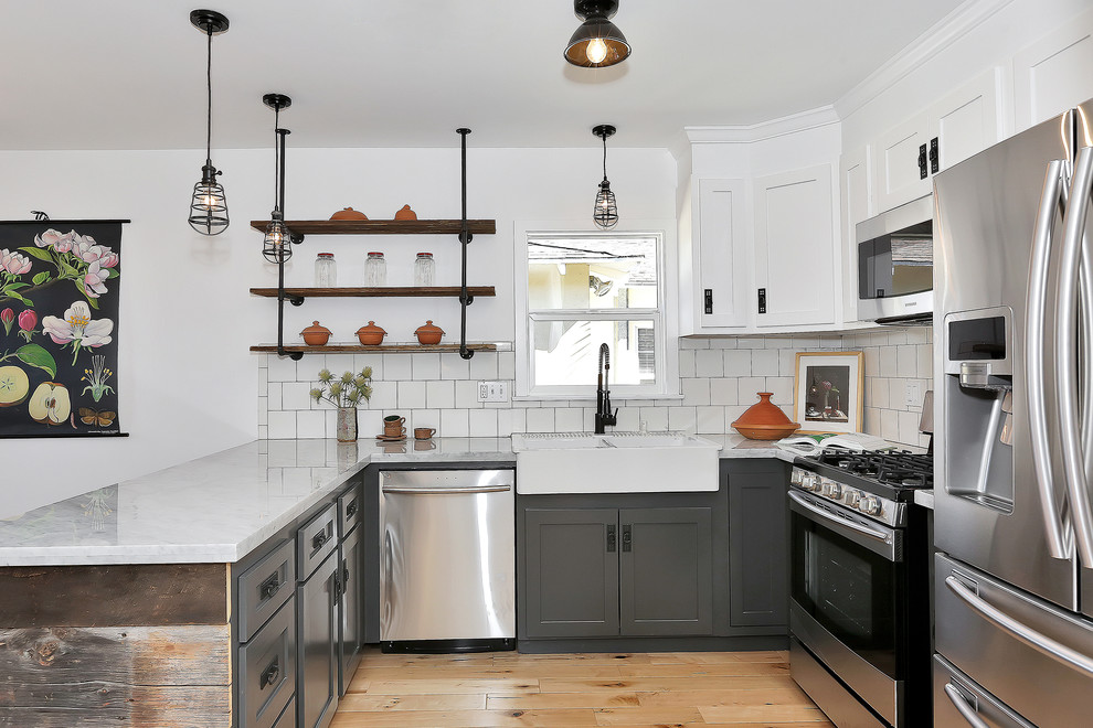 Inspiration for a transitional u-shaped kitchen remodel in Los Angeles with a farmhouse sink, shaker cabinets, white cabinets, white backsplash and stainless steel appliances