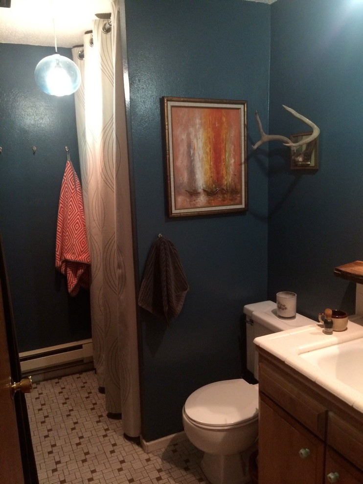 Small modern 3/4 bathroom in Seattle with an undermount sink, raised-panel cabinets, medium wood cabinets, tile benchtops, an alcove shower, a two-piece toilet, white tile, ceramic tile, blue walls and porcelain floors.