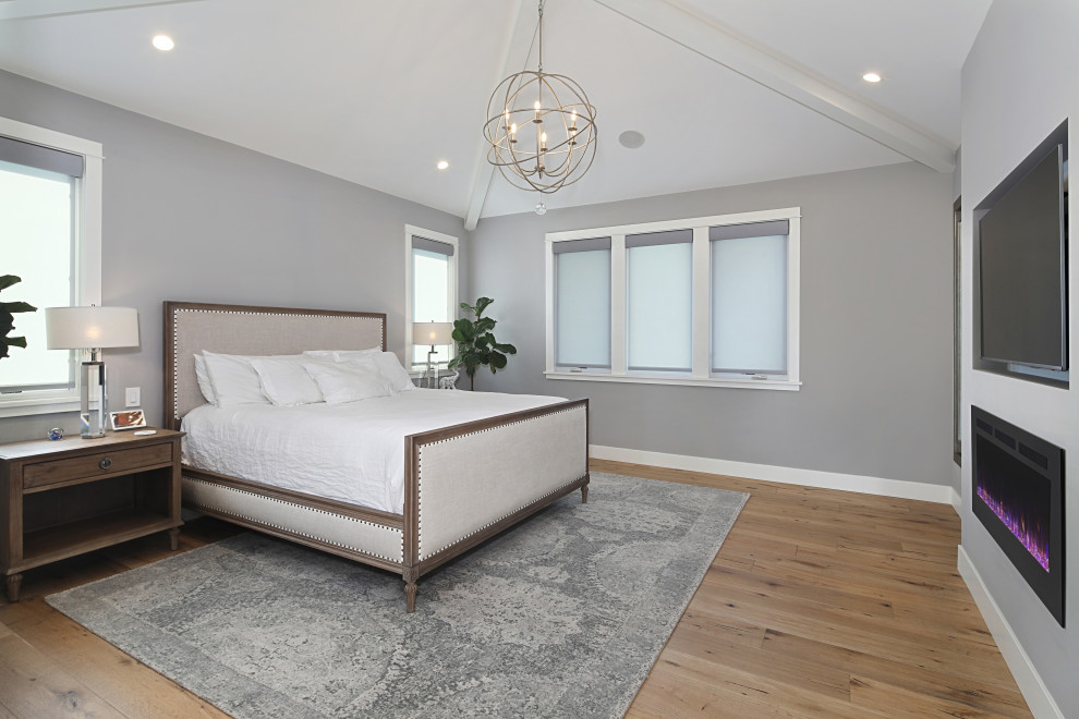 На фото: хозяйская спальня среднего размера в стиле неоклассика (современная классика) с серыми стенами, светлым паркетным полом, стандартным камином и сводчатым потолком