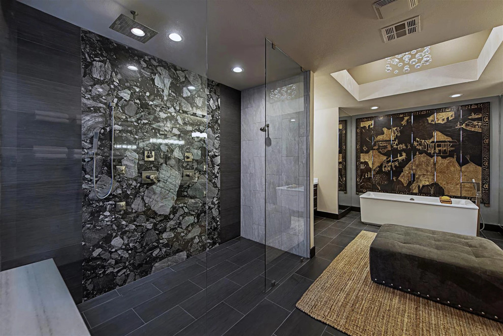 Inspiration for a large asian master bathroom in Las Vegas with flat-panel cabinets, black cabinets, a freestanding tub, an open shower, a one-piece toilet, gray tile, grey walls, granite benchtops, black floor, an open shower, porcelain tile, porcelain floors, a vessel sink and white benchtops.