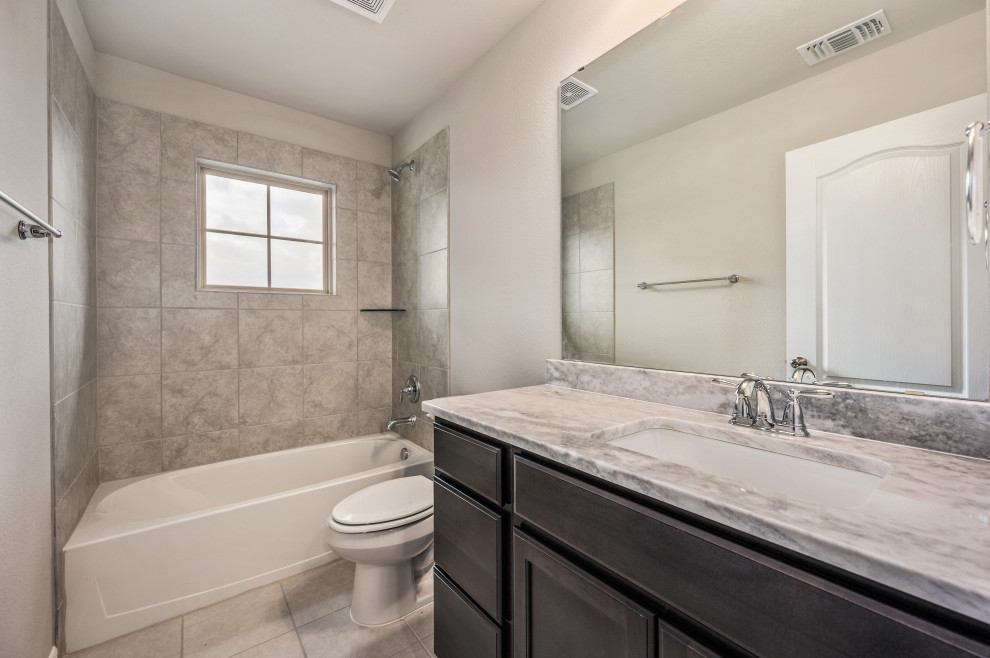 Medium sized traditional family bathroom in Austin with shaker cabinets, dark wood cabinets, an alcove bath, a shower/bath combination, a one-piece toilet, grey tiles, ceramic tiles, grey walls, cement flooring, a submerged sink, granite worktops, beige floors, a shower curtain, grey worktops, a single sink and a built in vanity unit.