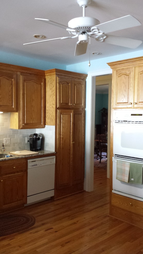 Example of a transitional kitchen design with shaker cabinets, white cabinets and an island