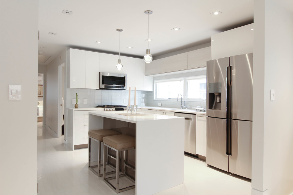 This is an example of a mid-sized contemporary l-shaped eat-in kitchen in New York with an undermount sink, flat-panel cabinets, white cabinets, quartzite benchtops, white splashback, glass tile splashback, stainless steel appliances, ceramic floors and with island.