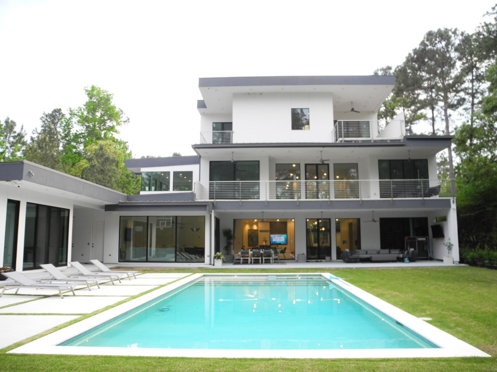 Ejemplo de fachada de casa blanca y blanca minimalista extra grande de tres plantas con revestimiento de estuco, tejado plano y tejado de metal