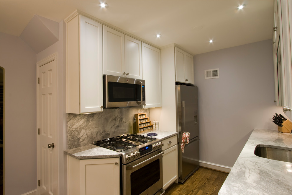 Inspiration for a small transitional galley medium tone wood floor enclosed kitchen remodel in DC Metro with an undermount sink, recessed-panel cabinets, white cabinets, quartz countertops, gray backsplash, stone slab backsplash, stainless steel appliances and no island