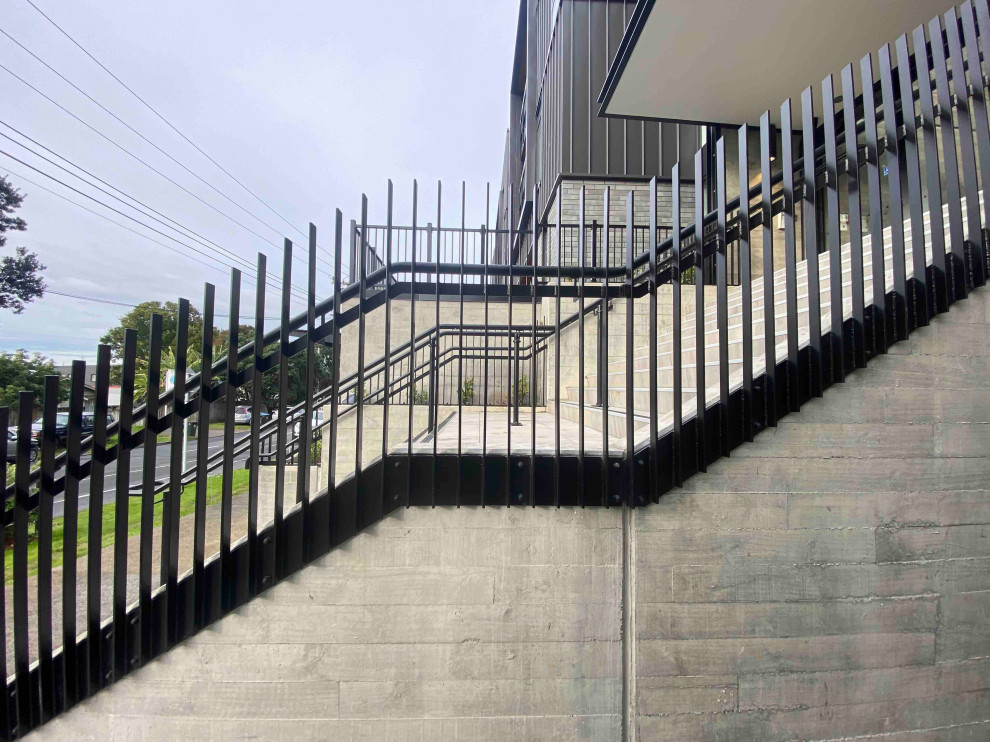 Medium sized modern concrete straight metal railing staircase in Auckland with concrete risers.