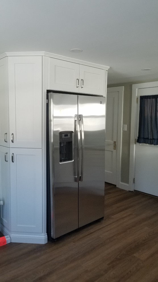 Small traditional l-shaped separate kitchen in Boston with an undermount sink, shaker cabinets, white cabinets, granite benchtops, green splashback, subway tile splashback, stainless steel appliances, vinyl floors, no island, brown floor and grey benchtop.