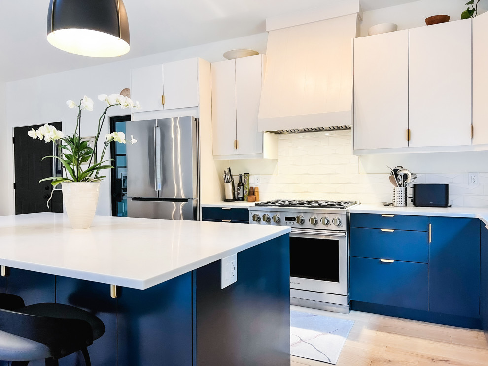 Nordisk inredning av ett stort vit vitt kök, med en undermonterad diskho, släta luckor, blå skåp, bänkskiva i kvarts, rostfria vitvaror, ljust trägolv, en köksö och beiget golv