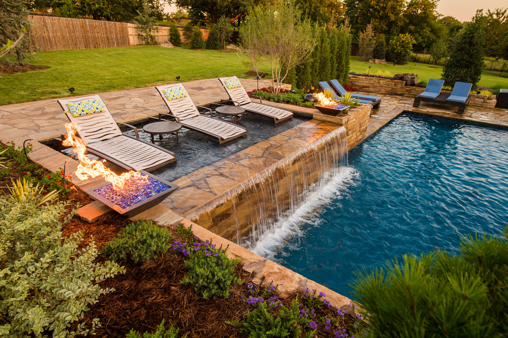 This is an example of a mid-sized modern backyard rectangular lap pool in Oklahoma City with a water feature and natural stone pavers.