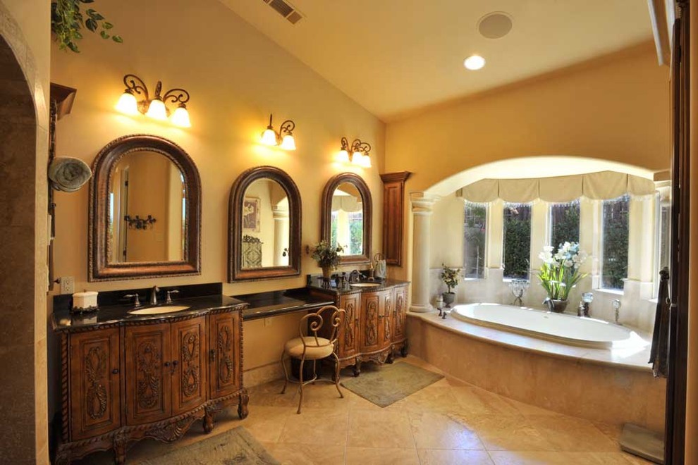 Large mediterranean master bathroom in Sacramento with furniture-like cabinets, dark wood cabinets, a drop-in tub, beige tile, stone tile, beige walls, travertine floors, an undermount sink, engineered quartz benchtops and beige floor.