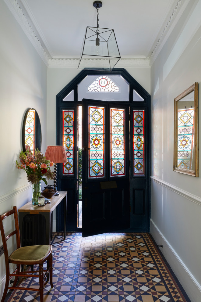 Ispirazione per un corridoio vittoriano di medie dimensioni con pareti grigie, pavimento con piastrelle in ceramica, una porta singola, una porta blu e pavimento multicolore