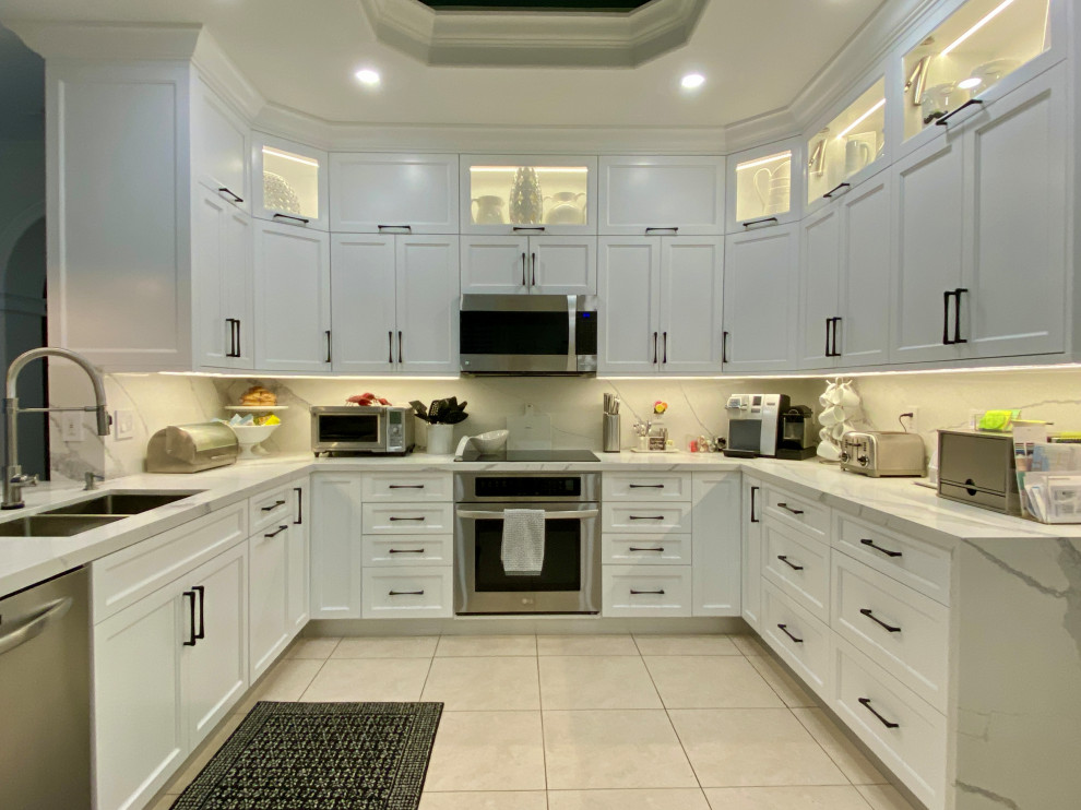 Open concept kitchen - transitional u-shaped porcelain tile, beige floor and coffered ceiling open concept kitchen idea in Miami with a double-bowl sink, shaker cabinets, white cabinets, quartz countertops, white backsplash, quartz backsplash, stainless steel appliances, a peninsula and white countertops