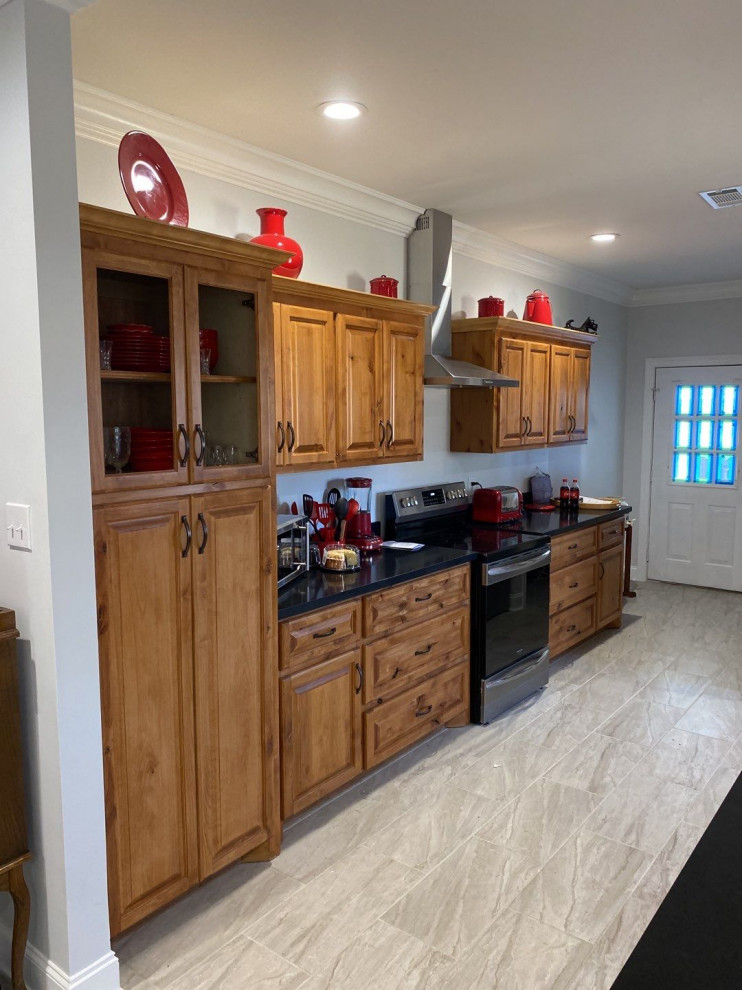 Kitchen - ceramic tile and gray floor kitchen idea with medium tone wood cabinets, quartz countertops, stainless steel appliances and black countertops