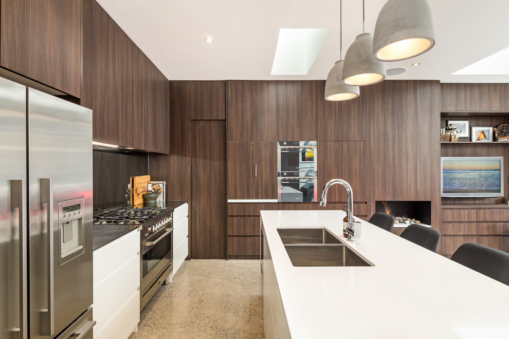 Design ideas for a mid-sized contemporary galley open plan kitchen in Sydney with a double-bowl sink, recessed-panel cabinets, brown cabinets, marble benchtops, metallic splashback, mirror splashback, stainless steel appliances, concrete floors and with island.