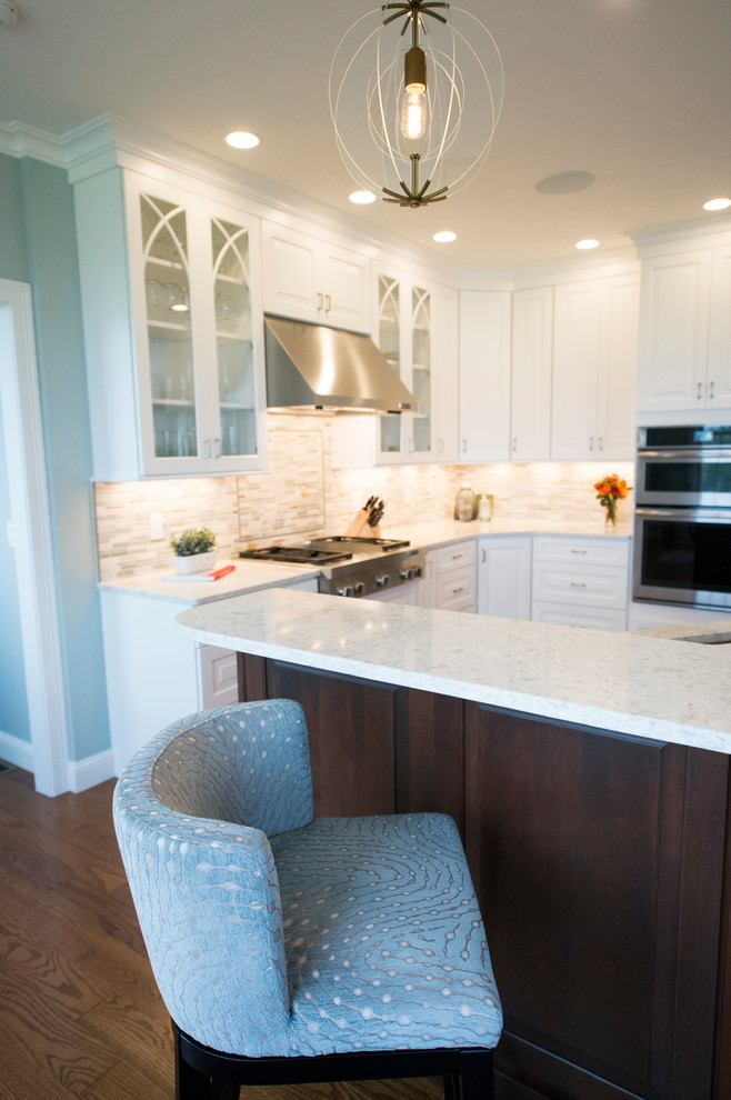 Eat-in kitchen - transitional l-shaped medium tone wood floor eat-in kitchen idea in Boston with white cabinets, granite countertops, gray backsplash, stainless steel appliances and an island