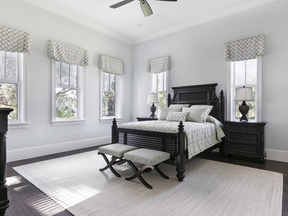Photo of a large beach style master bedroom in Orlando with grey walls, dark hardwood floors, no fireplace and brown floor.