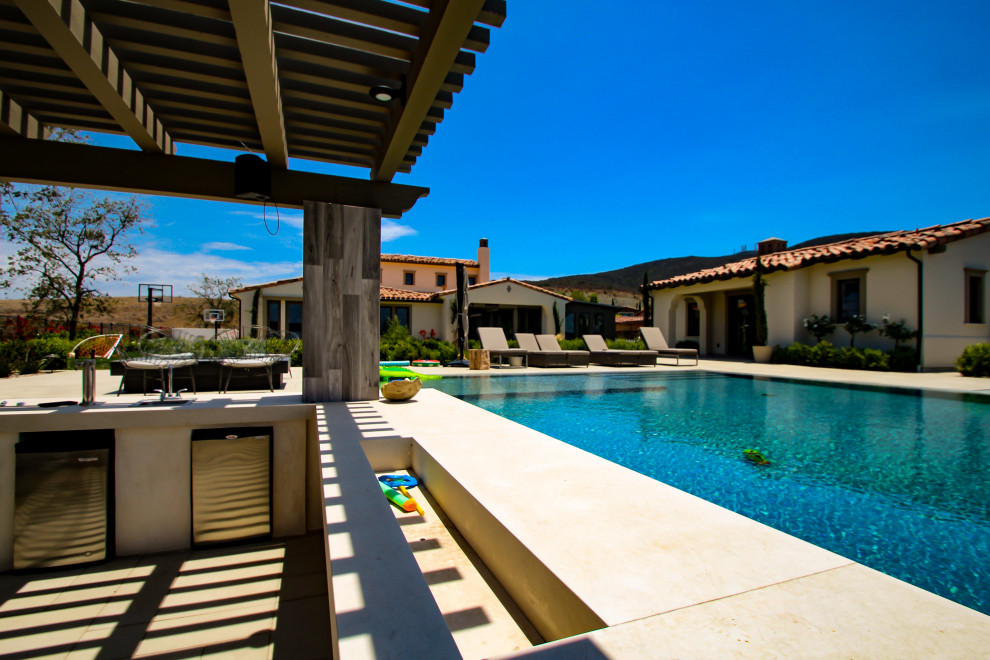Inspiration for a large contemporary backyard rectangular infinity pool in San Diego with with a pool and tile.