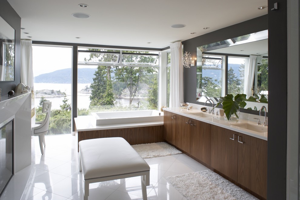 Design ideas for a modern bathroom in Vancouver with an undermount sink, flat-panel cabinets, dark wood cabinets, a drop-in tub, black walls and white benchtops.