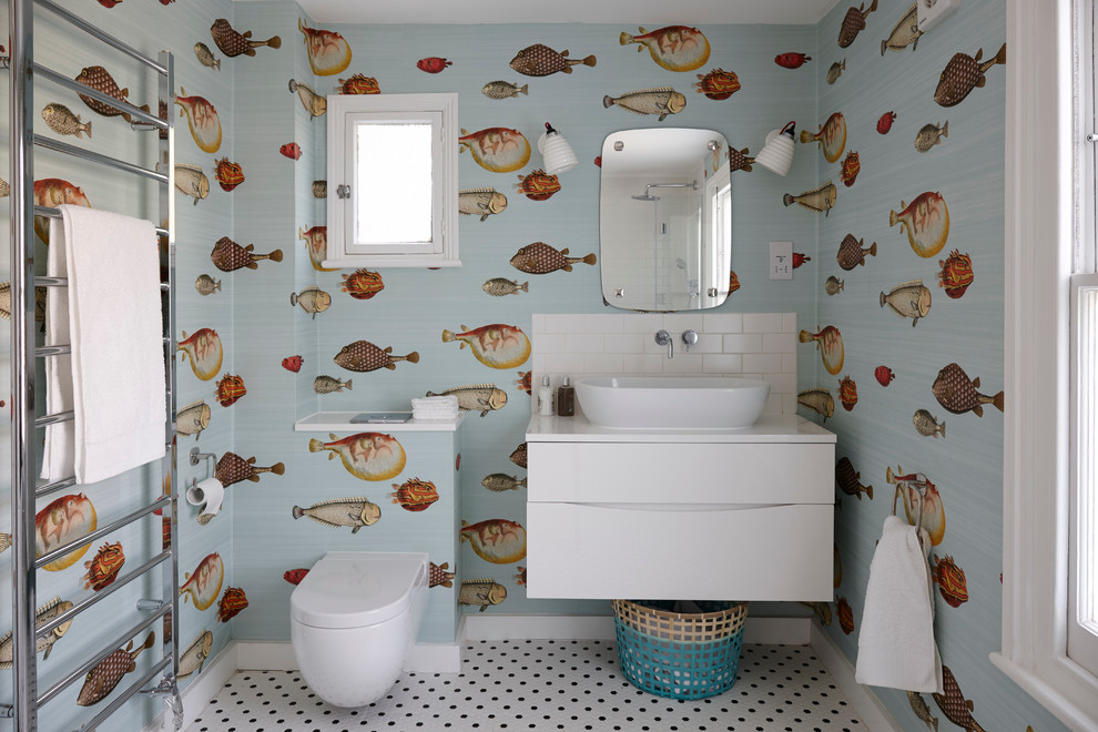 Design ideas for a mid-sized beach style kids bathroom in London with flat-panel cabinets, white cabinets, quartzite benchtops, multi-coloured walls, ceramic floors, a vessel sink, a one-piece toilet, white tile and subway tile.