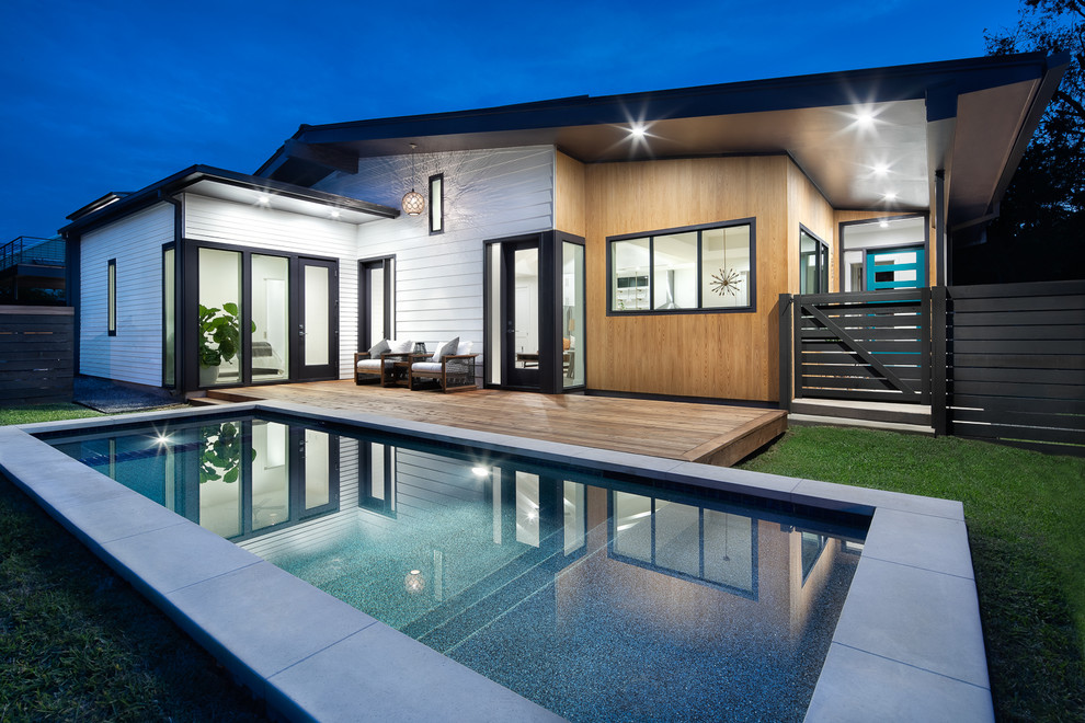 This is an example of a large midcentury backyard rectangular lap pool in Austin with decking.