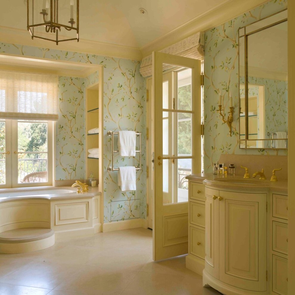 Inspiration for a large traditional master bathroom with raised-panel cabinets, beige cabinets, a corner tub, blue walls, ceramic floors, a drop-in sink and beige floor.