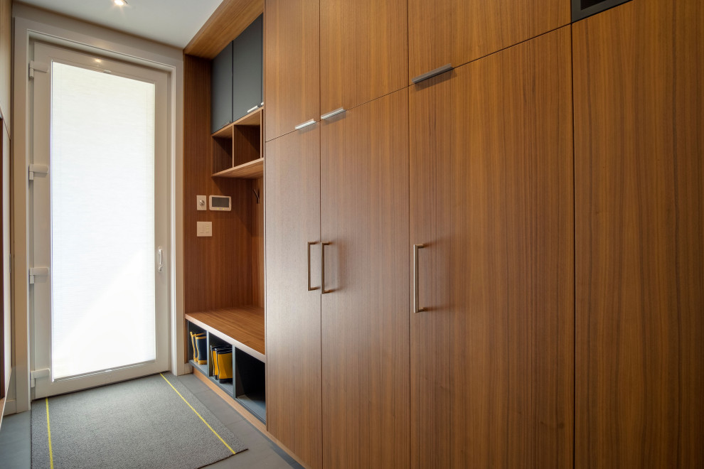 Imagen de armario y vestidor minimalista grande con a medida, armarios con paneles lisos, puertas de armario de madera oscura y suelo de cemento