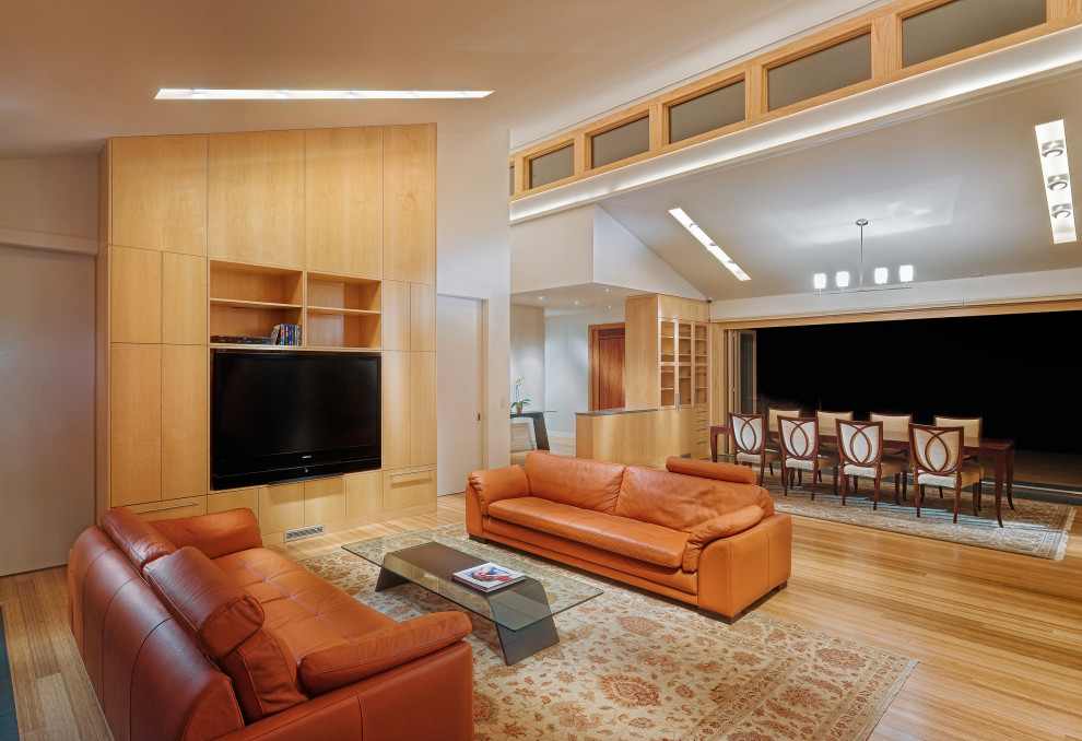 Modern inredning av ett öppen hemmabio, med beige väggar, ljust trägolv, en inbyggd mediavägg och beiget golv