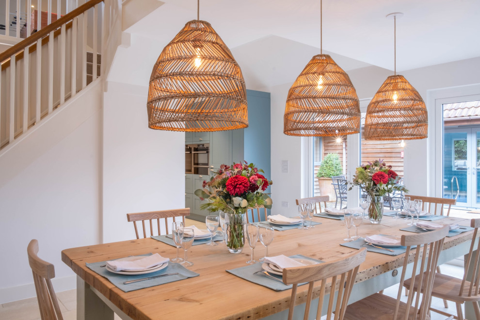 Mid-sized country open plan dining in Gloucestershire with white walls, porcelain floors, a wood stove and beige floor.