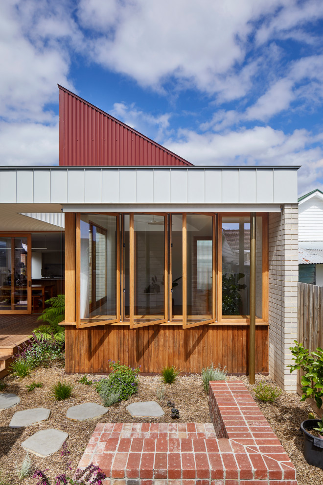 Immagine della villa piccola marrone contemporanea a un piano con rivestimento in legno, tetto piano, copertura in metallo o lamiera, tetto rosso e pannelli e listelle di legno