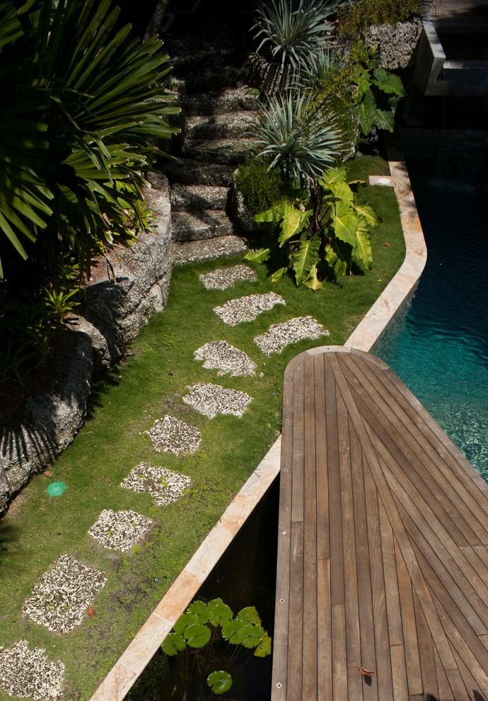 Inspiration for a large tropical backyard deck in Miami with a water feature.