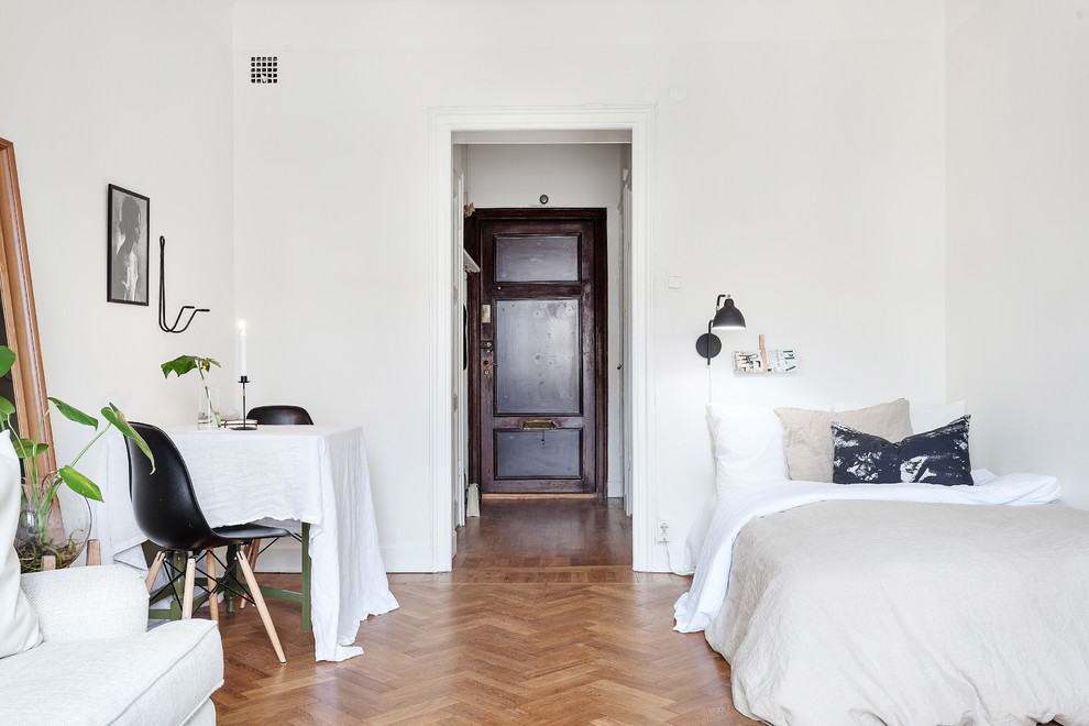 This is an example of a large scandinavian master bedroom in Stockholm with white walls and medium hardwood floors.