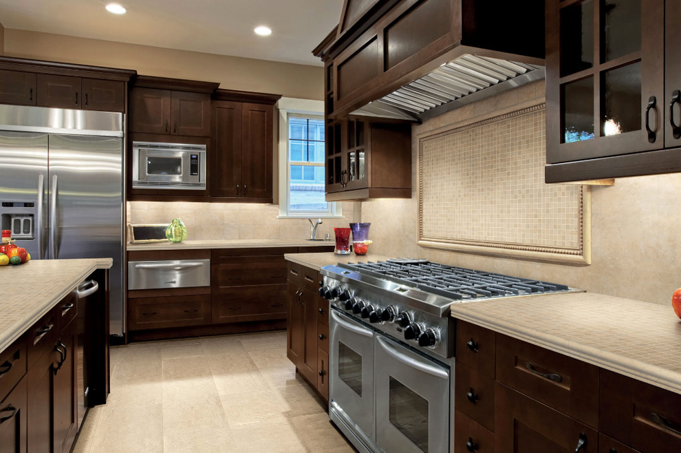 Inspiration for a large l-shaped ceramic tile kitchen remodel in Phoenix with tile countertops, beige backsplash, stainless steel appliances, an island, an undermount sink, shaker cabinets, dark wood cabinets and porcelain backsplash