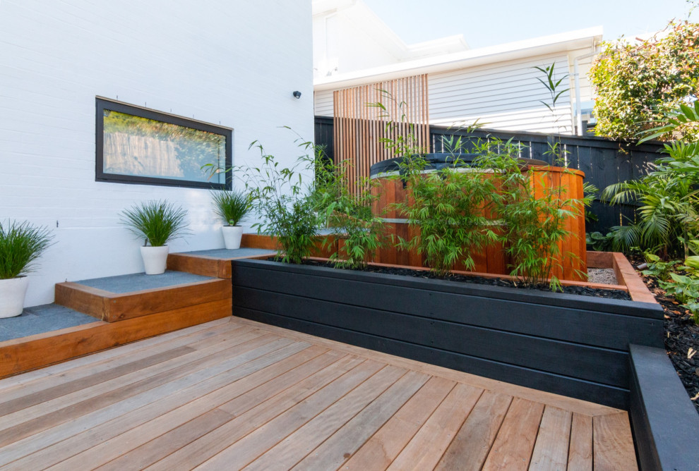 This is an example of a large tropical backyard deck in Auckland.