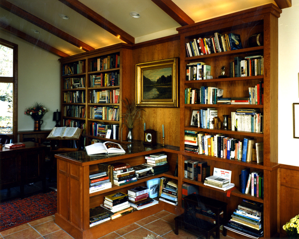 На фото: домашняя библиотека среднего размера в стиле кантри с белыми стенами, полом из терракотовой плитки, стандартным камином и фасадом камина из плитки