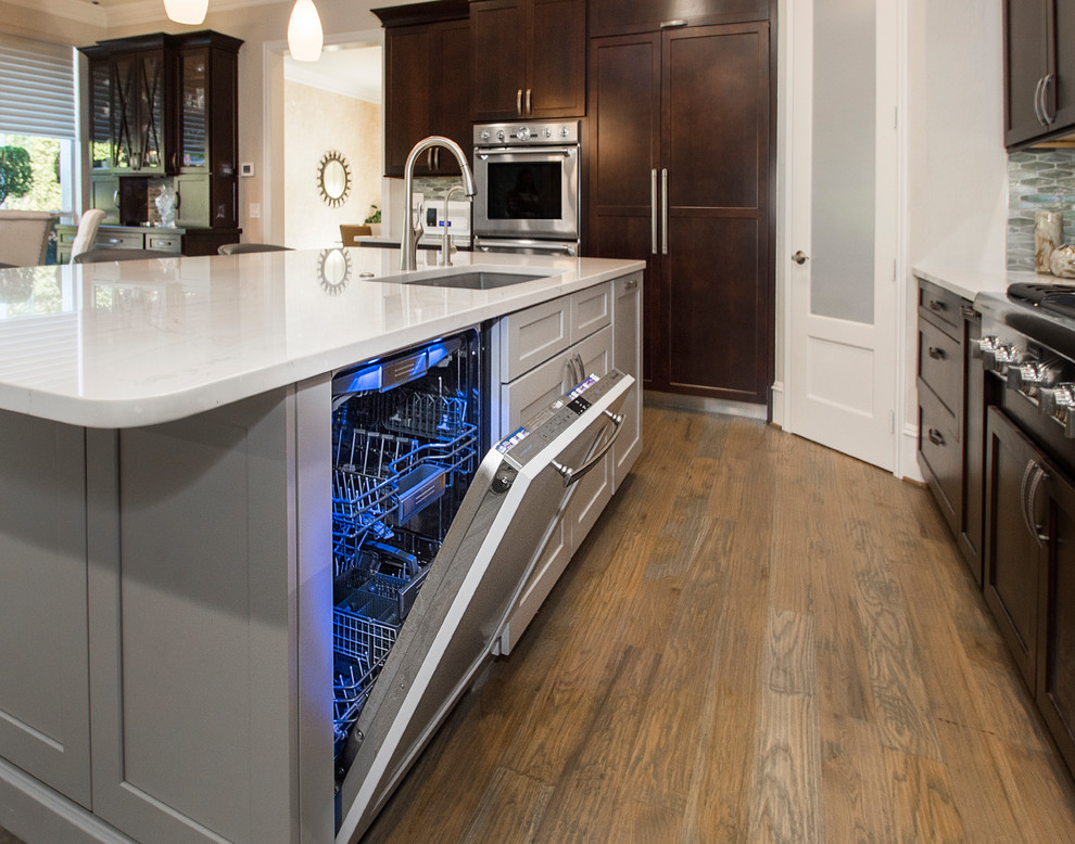 Inspiration for a mid-sized transitional l-shaped medium tone wood floor and brown floor open concept kitchen remodel in DC Metro with an undermount sink, recessed-panel cabinets, dark wood cabinets, granite countertops, beige backsplash, ceramic backsplash, stainless steel appliances, an island and beige countertops