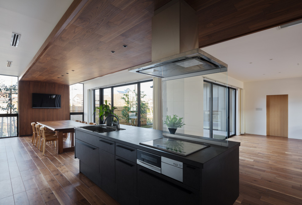 Photo of a large modern single-wall open plan kitchen in Fukuoka with an integrated sink, flat-panel cabinets, grey cabinets, solid surface benchtops, stainless steel appliances, plywood floors, with island, brown floor and grey benchtop.
