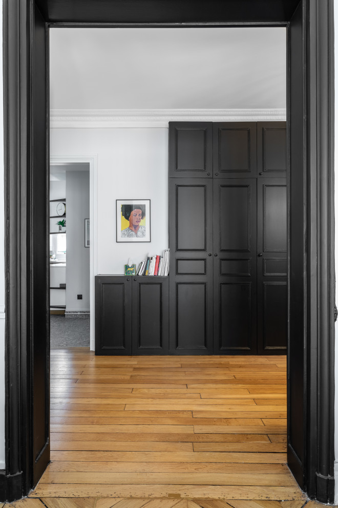 This is an example of a large contemporary foyer in Paris with white walls, light hardwood flooring, a single front door, a black front door and brown floors.