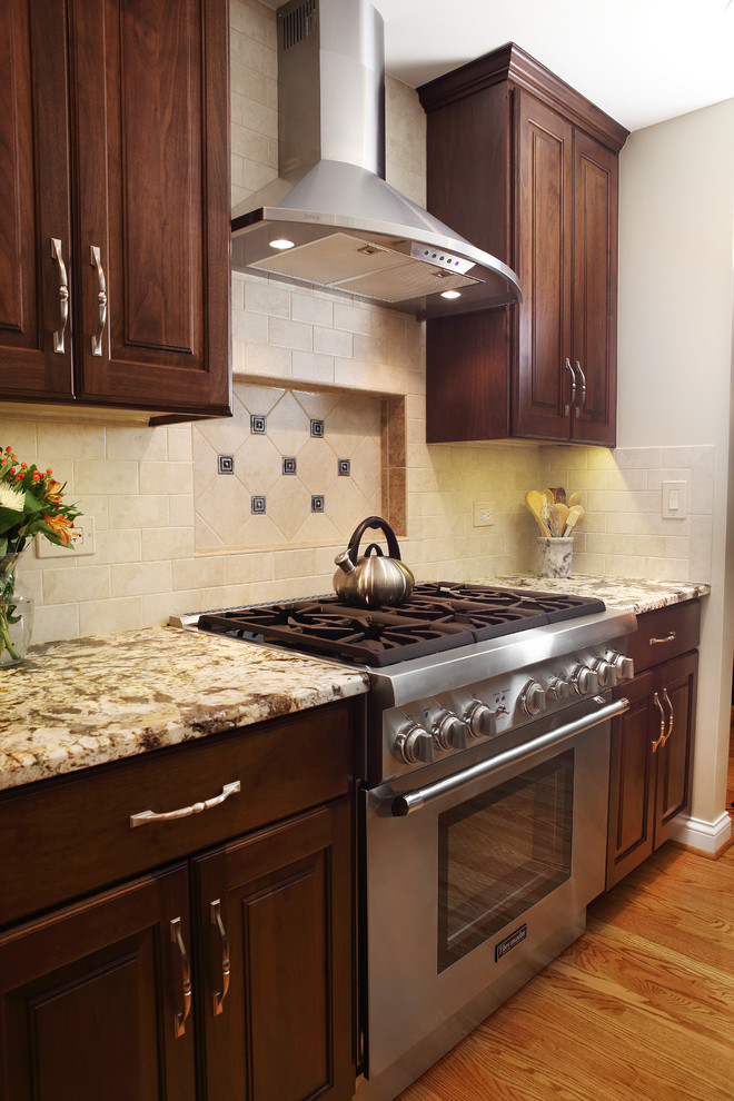 Eat-in kitchen - large transitional l-shaped medium tone wood floor eat-in kitchen idea in Chicago with an undermount sink, raised-panel cabinets, medium tone wood cabinets, granite countertops, beige backsplash, subway tile backsplash, stainless steel appliances and an island