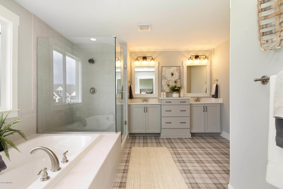 Photo of a large transitional master bathroom in Grand Rapids with recessed-panel cabinets, grey cabinets, a drop-in tub, a corner shower, gray tile, porcelain tile, grey walls, vinyl floors, multi-coloured floor and a hinged shower door.