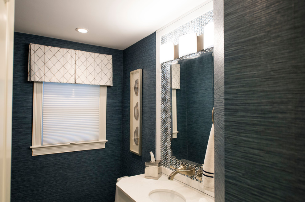 Inspiration for a small transitional powder room in Boston with flat-panel cabinets, white cabinets, a one-piece toilet, blue tile, glass sheet wall, blue walls, ceramic floors, an undermount sink and beige floor.